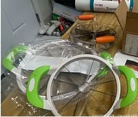 Green/white apple slicer and orange circular cutter on counter
