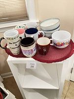 Group shot of all mugs and stacked bowls on red mat