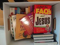Box containing assorted books with titles facing outward