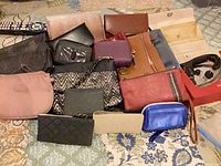 Group shot of assorted wallets, clutches, pouches on bed