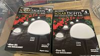 Front of both sealed boxes showing Bell+Howell branding and product image