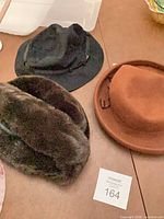 Three hats near lot tag 164: black felt hat, brown faux-fur hat, brown cloche hat