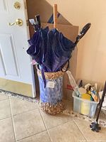 Umbrella stand positioned by doorway containing multiple umbrellas