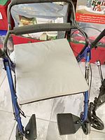 Blue rollator with grey seat cushion visible