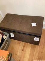 Closed view of brown fabric storage bench with tufted top