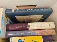 Box of assorted Christian books, spines visible including Pursuit of His Presence, Moses, God Will Make a Way