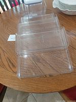 stack of clear plastic trays and tall container with lid on table