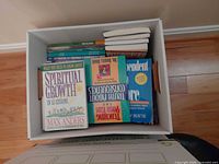 Top view of box showing multiple paperback books including Spiritual Growth in 12 Lessons and Codependent No More