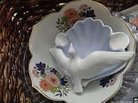 Top view of basket showing floral porcelain dish, blue shell dish, white dove figurine