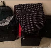 Group of suitcases against wall; black carry-on lower left showing wheels and fabric exterior
