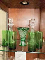 All items on glass shelf: green vase centred between four tumblers and two clear candlesticks