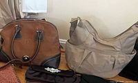 Brown satchel, beige shoulder bag, black satin clutch visible