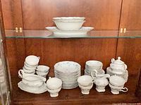 Cabinet view showing stacks of plates, cups, sugar bowl, creamer, serving pieces