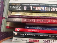 Stack of mixed hardcover and paperback books showing spines including Robeson Strongman’s His Name? II, Max Davis title, The Life You’ve Always Wanted and others