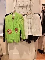 Front view showing green blazer and white jacket hung on rack