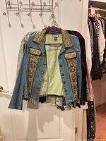Blue denim jacket with patterned trim on hanger