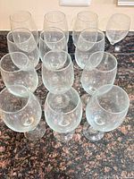 Front angled view showing all 12 clear stemmed wine glasses grouped on counter