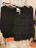 Front view of both black blouses on hangers