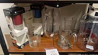 Shelf view with boxed Misto sprayers, glass pitcher, tumbler, beer stein, Viscan jug