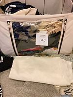 Bag containing folded tops, white knit sweater in foreground