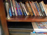 Shelf showing multiple paperback Christian books and metal vase