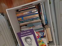 Box containing stack of paperbacks, children’s books in foreground