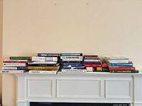 Full lot of stacked books on mantel showing quantity and variety