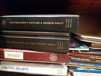 Stacked binders and spiral manuals showing two black Preacher's Outline & Sermon Bible binders, Old Testament Survey binder and Biblical Beliefs manual