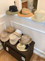 Seven assorted wide-brim hats displayed on chest and railing