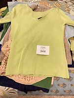 Lime green knit sweater on top of stacked garments