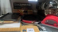 Overall lot showing red skillet, baking sheet, cutting boards, boxed items