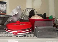 Overview of red silicone lids, metal trivets, red bowl with contents, wire dome, white bowl