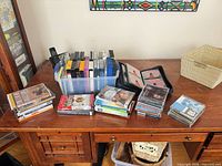 Overall lot with DVDs, VHS tapes in bin, CDs, disc wallet, wicker basket visible