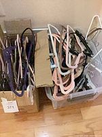Two containers filled with assorted hangers in multiple colours and materials
