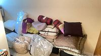 Pile of bedding items: comforter, pillows, shams, decorative cushions
