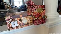 Two floral print storage boxes with gold hardware, one open showing lid