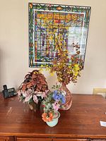 All three arrangements on wooden surface under artwork