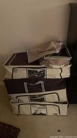 Stack of three beige canvas storage boxes with dark trim and vinyl windows