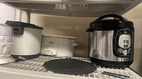 Group of four countertop appliances on shelf