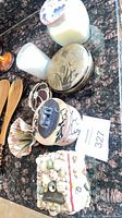 Group shot of shell-covered box, ceramic boxes, candle, wooden utensils