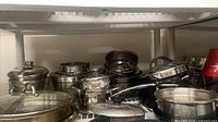 Assortment of stainless steel pots, pans and lids on shelf