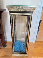 Front view of mirrored curio cabinet showing glass door, gold and black trim, and overall design