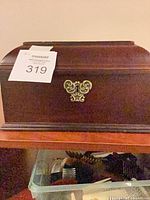 Closed mahogany jewelry box showing brass accent on front
