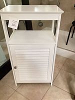 Front view of white accent cabinet with shutter door and open shelf