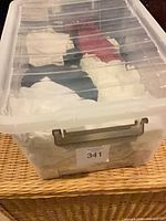 Clear plastic tote containing folded camisoles and tanks