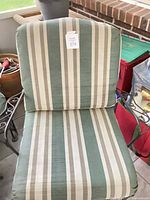 Striped cushion lounge chair showing upholstery and wrought iron arms