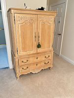 Front view of armoire with doors closed showing carved panels and drawers