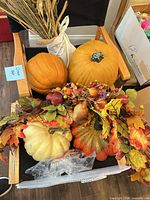 Group of decorative pumpkins, garland and dried grass displayed on chair