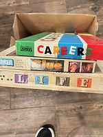 Stack of three board games—Careers, Clue, The Game of Life—inside a cardboard box