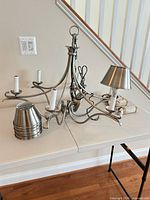 Chandelier frame, metal shades, canopy and chain on table
